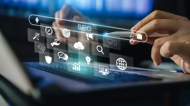 Pasek wyszukiwarki z ikonami SEO nad klawiaturą laptopa