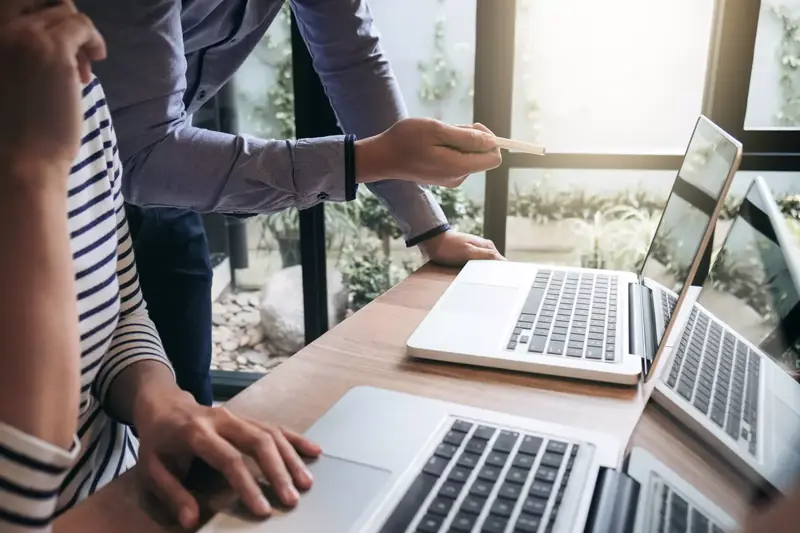 Dwie osoby omawiają projekt strony przy laptopach